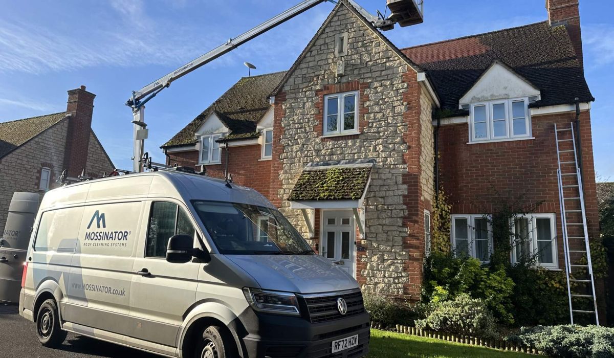 A van parked in front of a house, featuring a ladder secured on its roof.