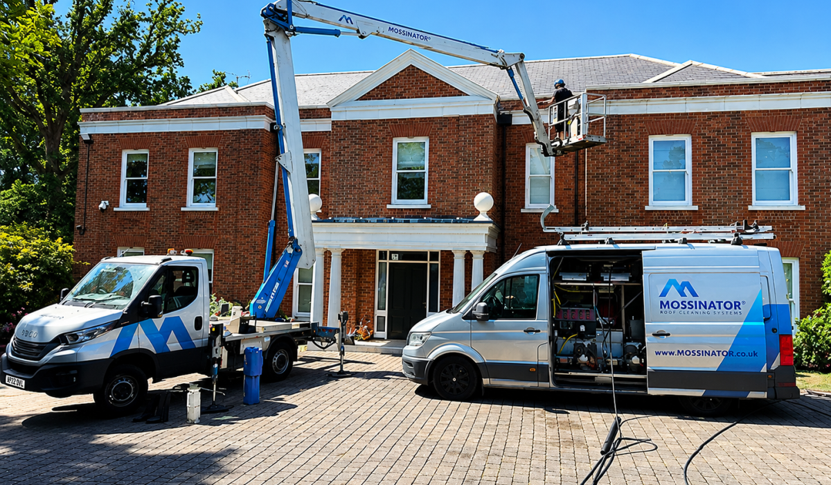 Mossinator team using a cherry picker and specialist roof cleaning equipment to clean the roof of a large residential property.