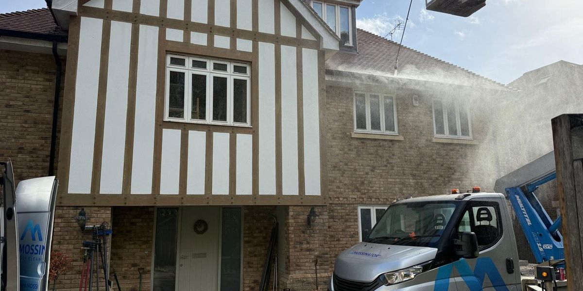 Mossinator technician cleaning roof tiles from a cherry picker at a home in Slough.